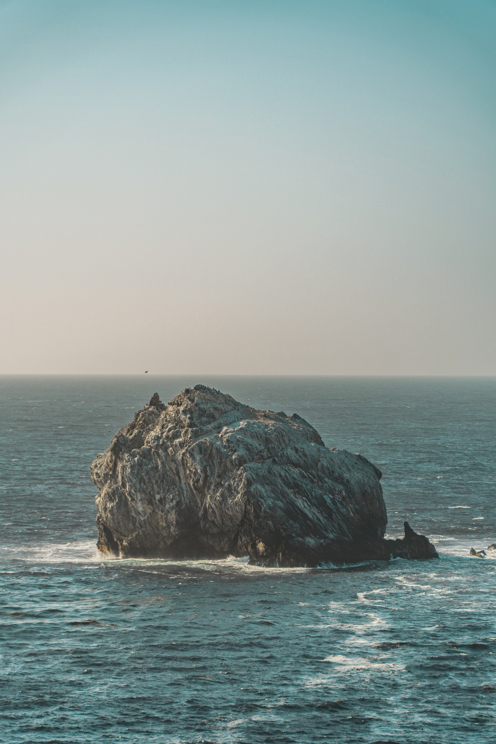 A photo of a lone boulder crowded with seagulls near Jade Cove, California