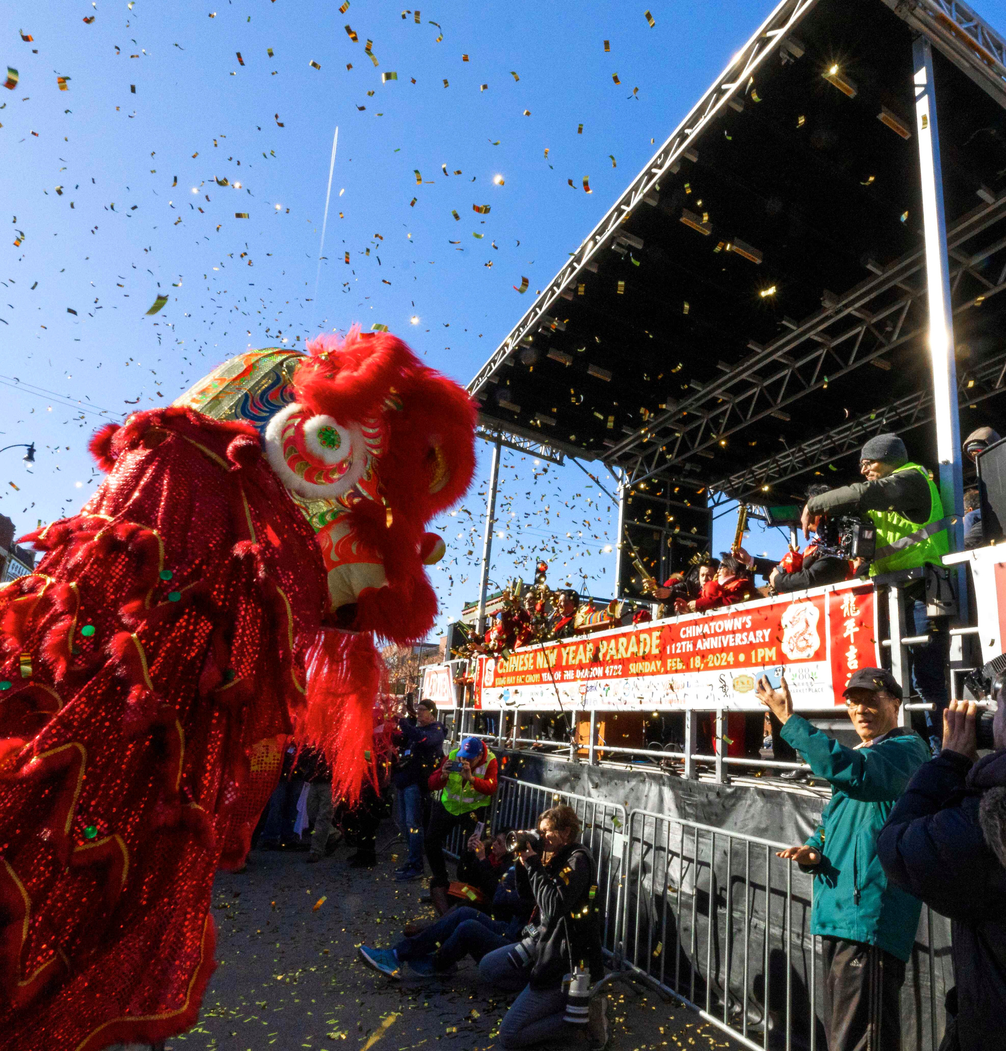Lion dance performance in front of the main stage at Chicago’s Chinatown Lunar New Year celebration, with gold confetti flying through the air.