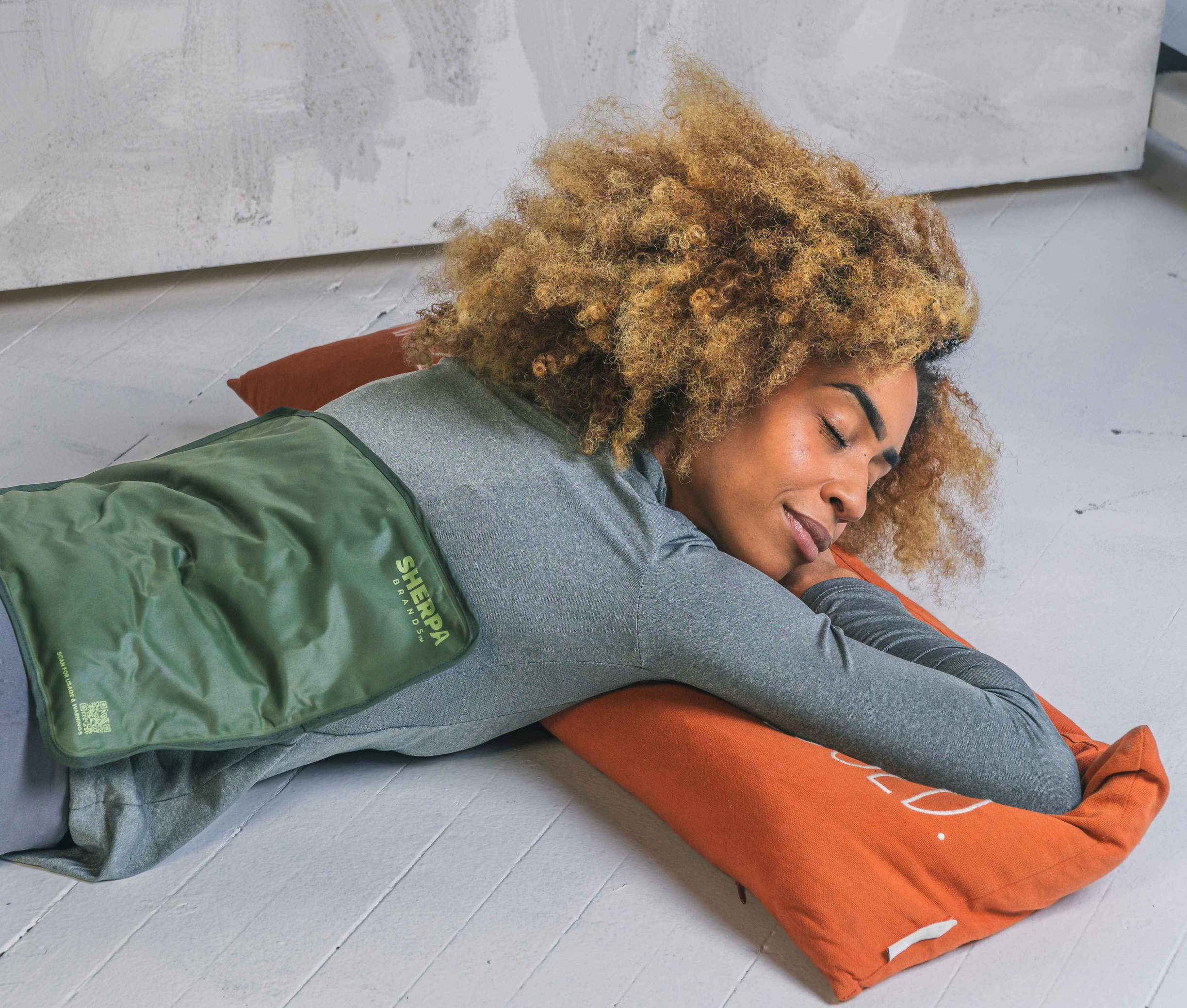 Woman lying on her stomach with an icepack placed on her upper back, promoting relief and comfort.