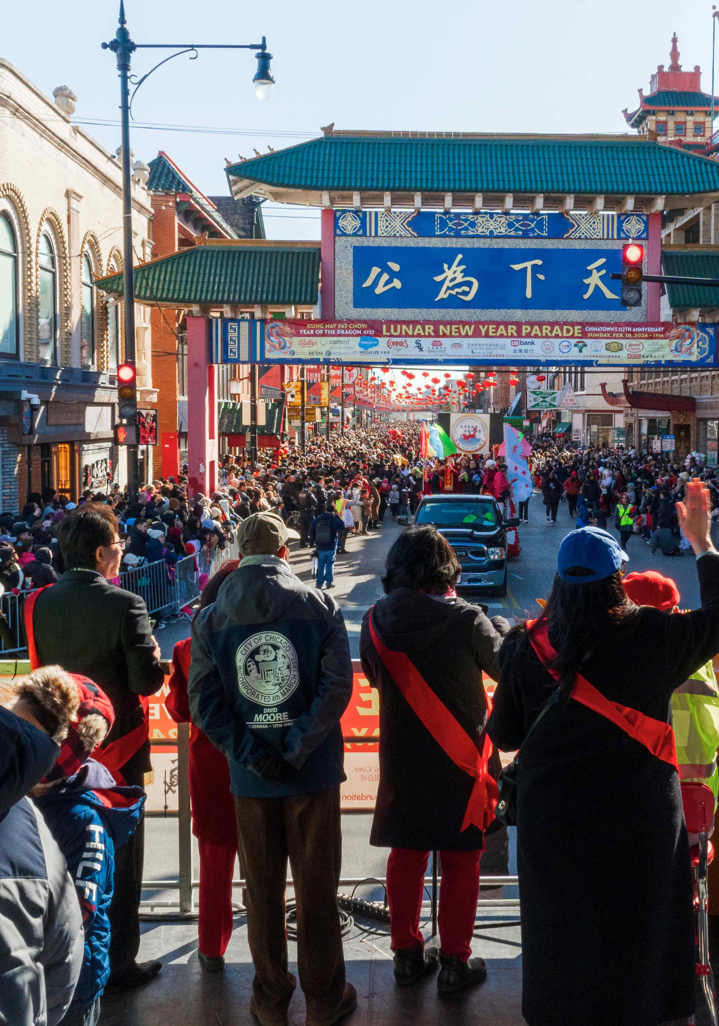 View from the main stage at Chicago’s Chinatown during the Lunar New Year celebration, showing parade floats passing by as announcements are made.